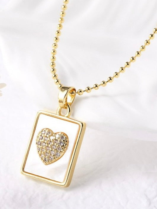 Gold necklace with a heart-shaped pendant on a white background