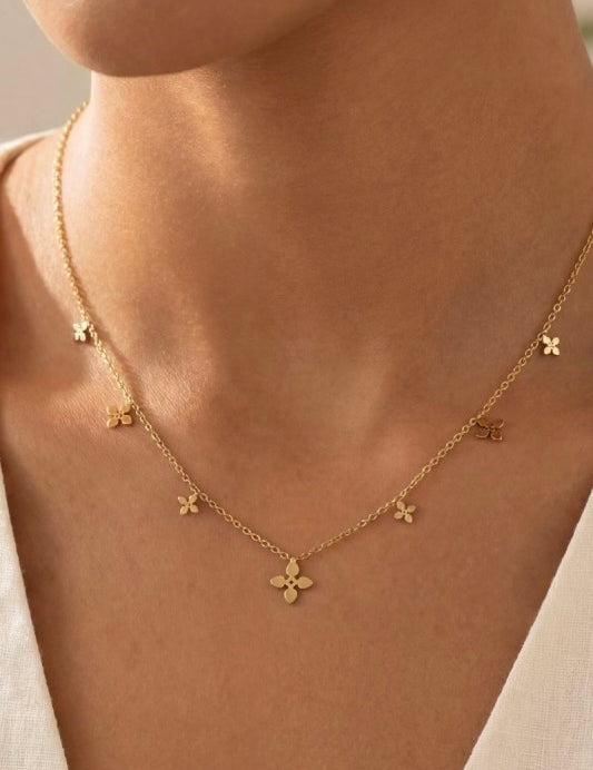 Gold necklace with floral pendants on a person's neck