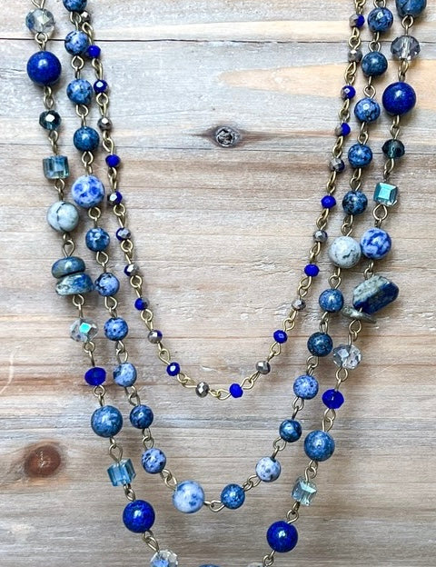 Multistrand necklace with blue and silver beads on a wooden surface