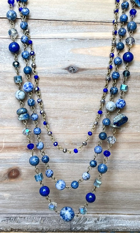 Multistrand necklace with blue and silver beads on a wooden surface
