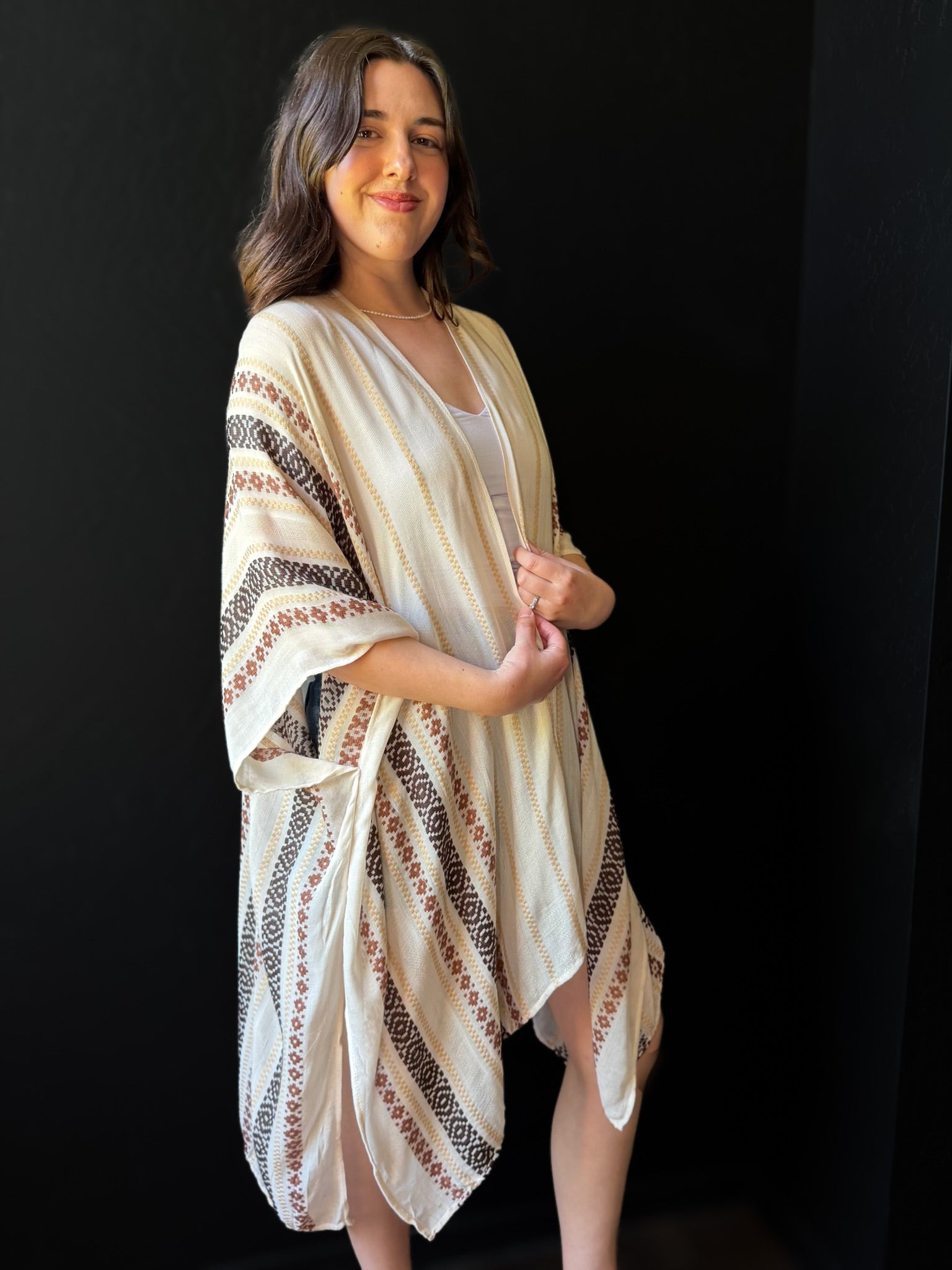 Woman wearing a beige patterned kimono-style garment against a black background