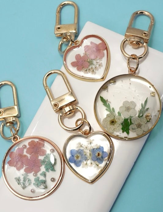 Heart-shaped keychains with floral designs on a white surface with a blue background