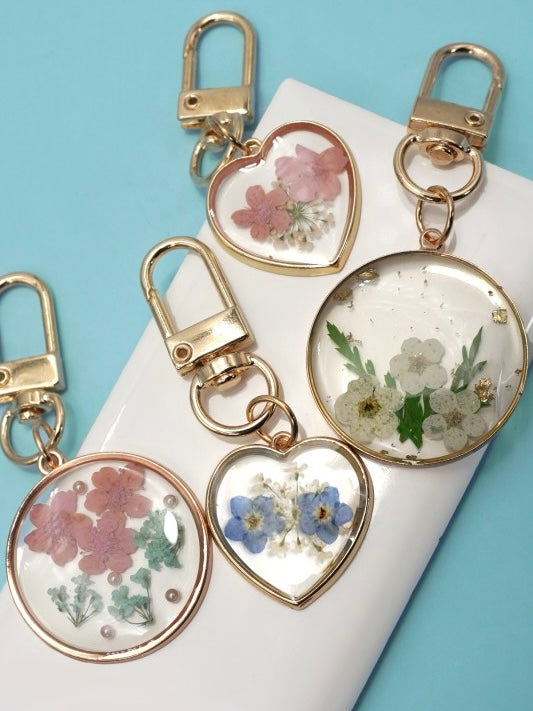 Heart-shaped keychains with floral designs on a white surface with a blue background