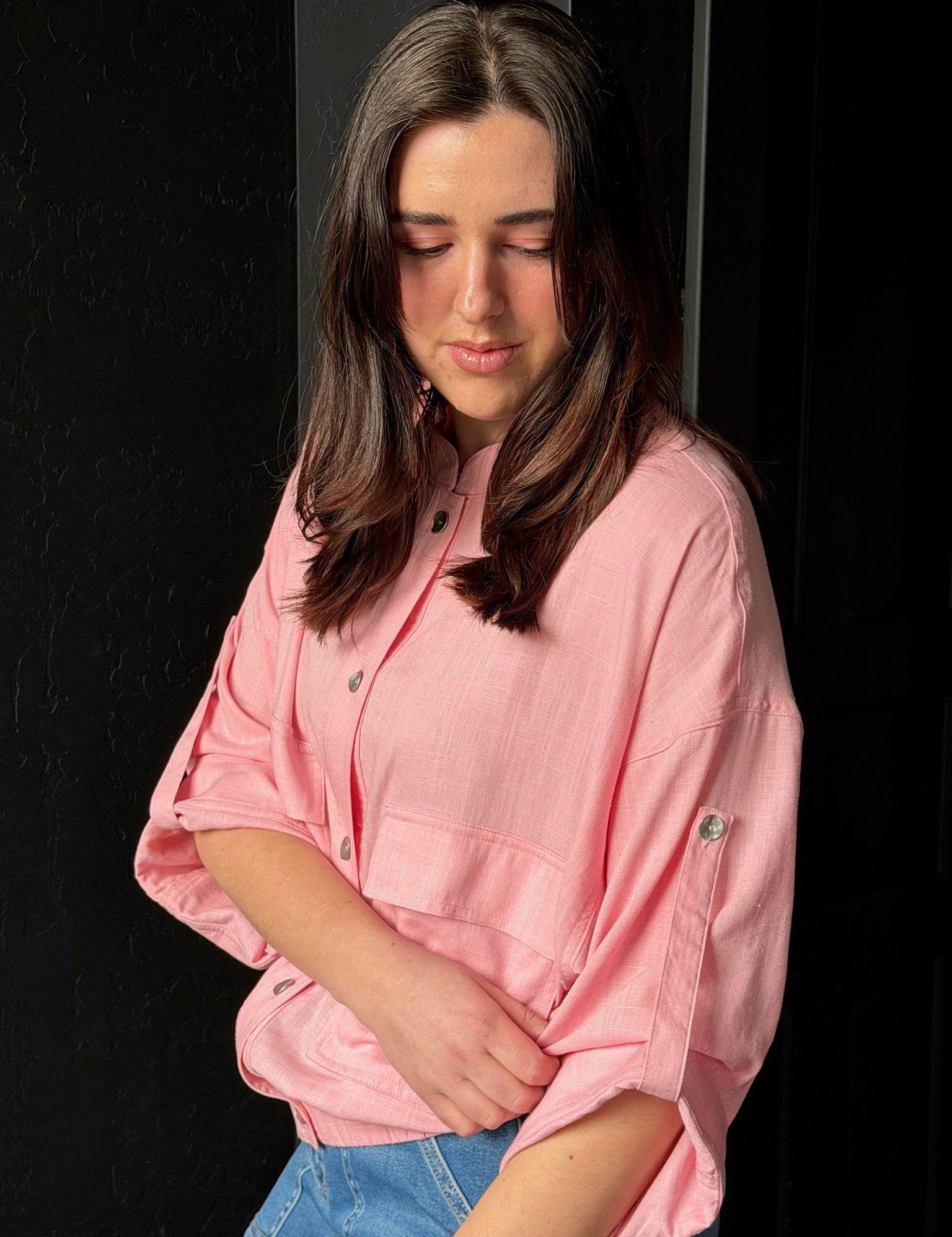 Woman wearing a pink shirt against a black background