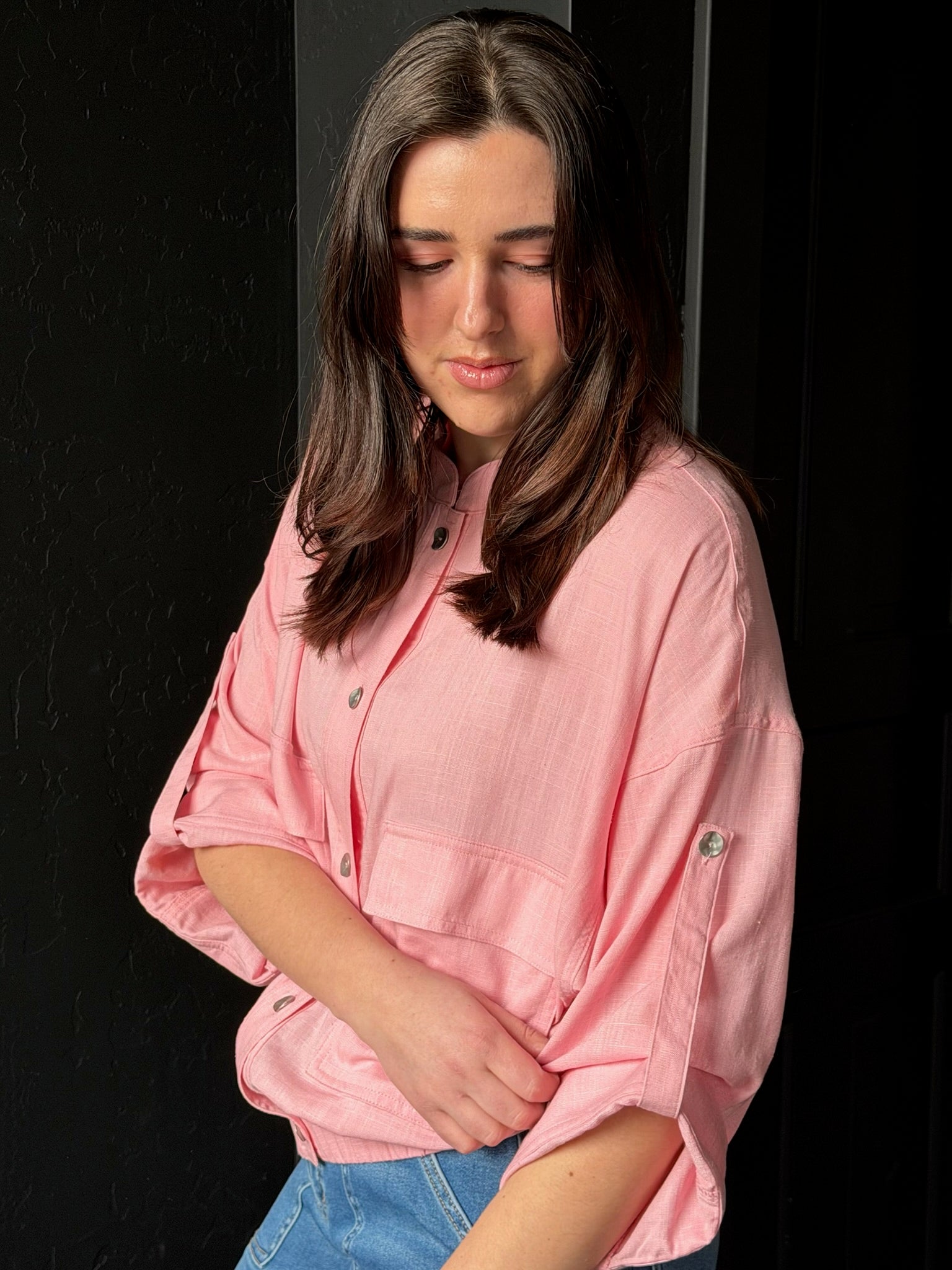 Woman wearing a pink shirt against a black background