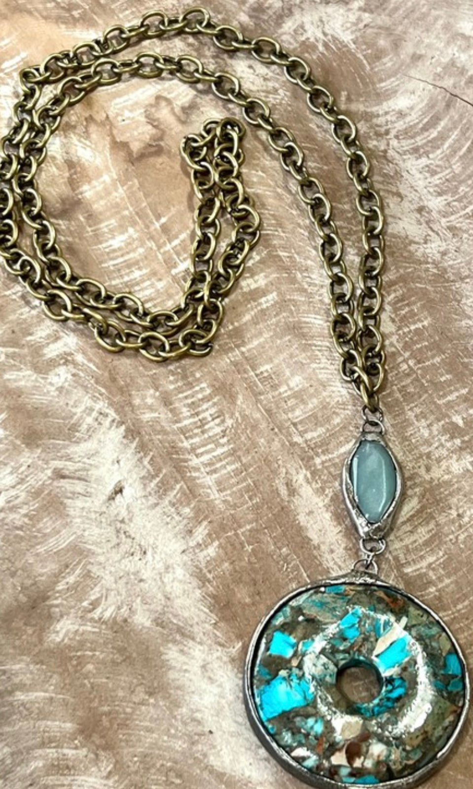Necklace with a turquoise pendant on a textured surface