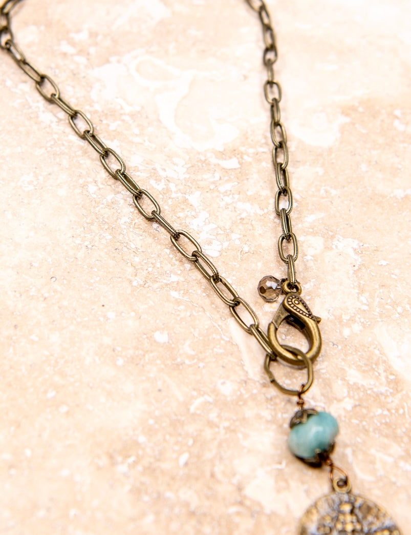 A beaded copper charm necklace with a turquoise pendant, featuring a chain link strand.