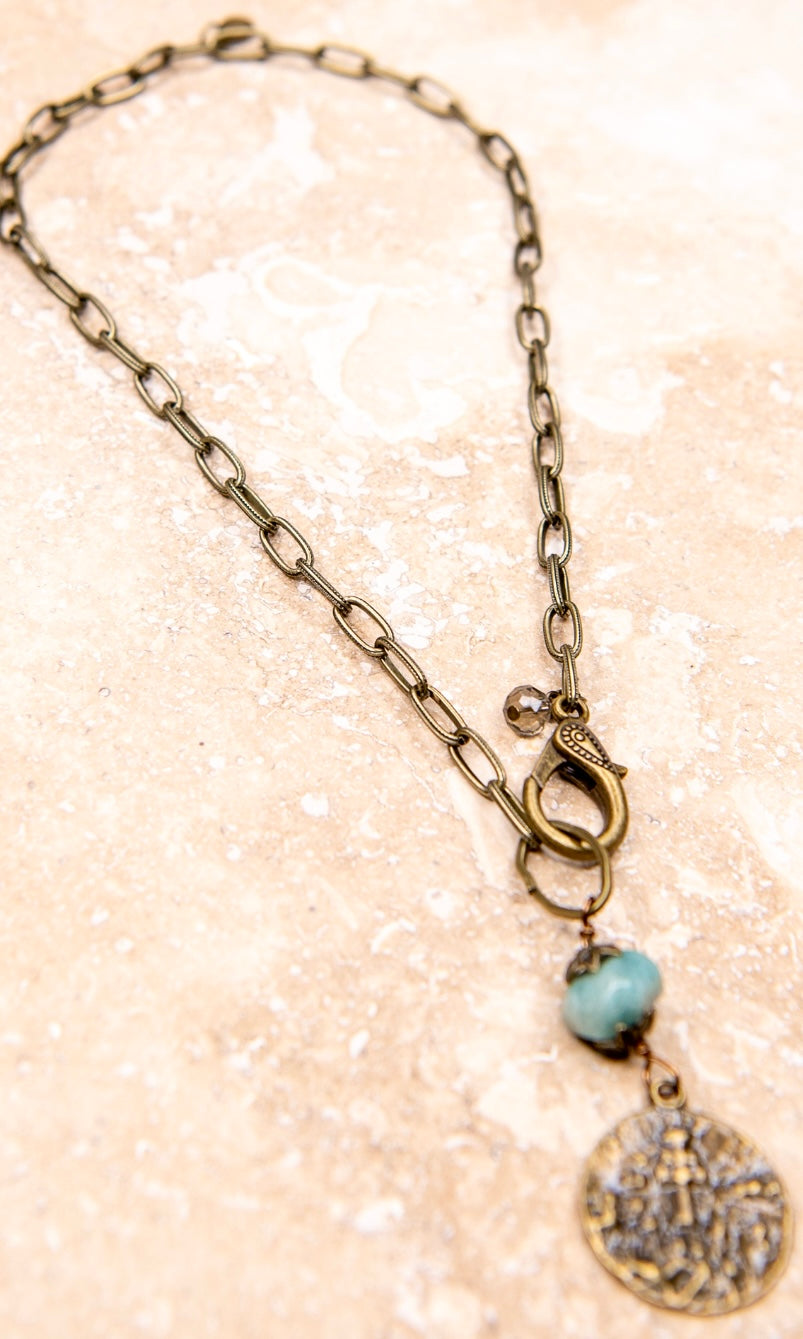 A beaded copper charm necklace with a turquoise pendant, featuring a chain link strand.