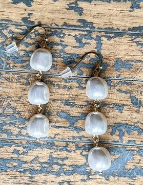 Pair of earrings with clear stones on a rustic wooden surface