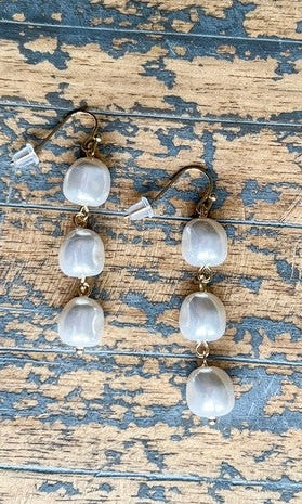 Pair of earrings with clear stones on a rustic wooden surface