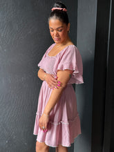 Woman wearing a pink dress against a dark gray wall