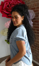 Woman wearing a denim jacket with floral decorations in the background