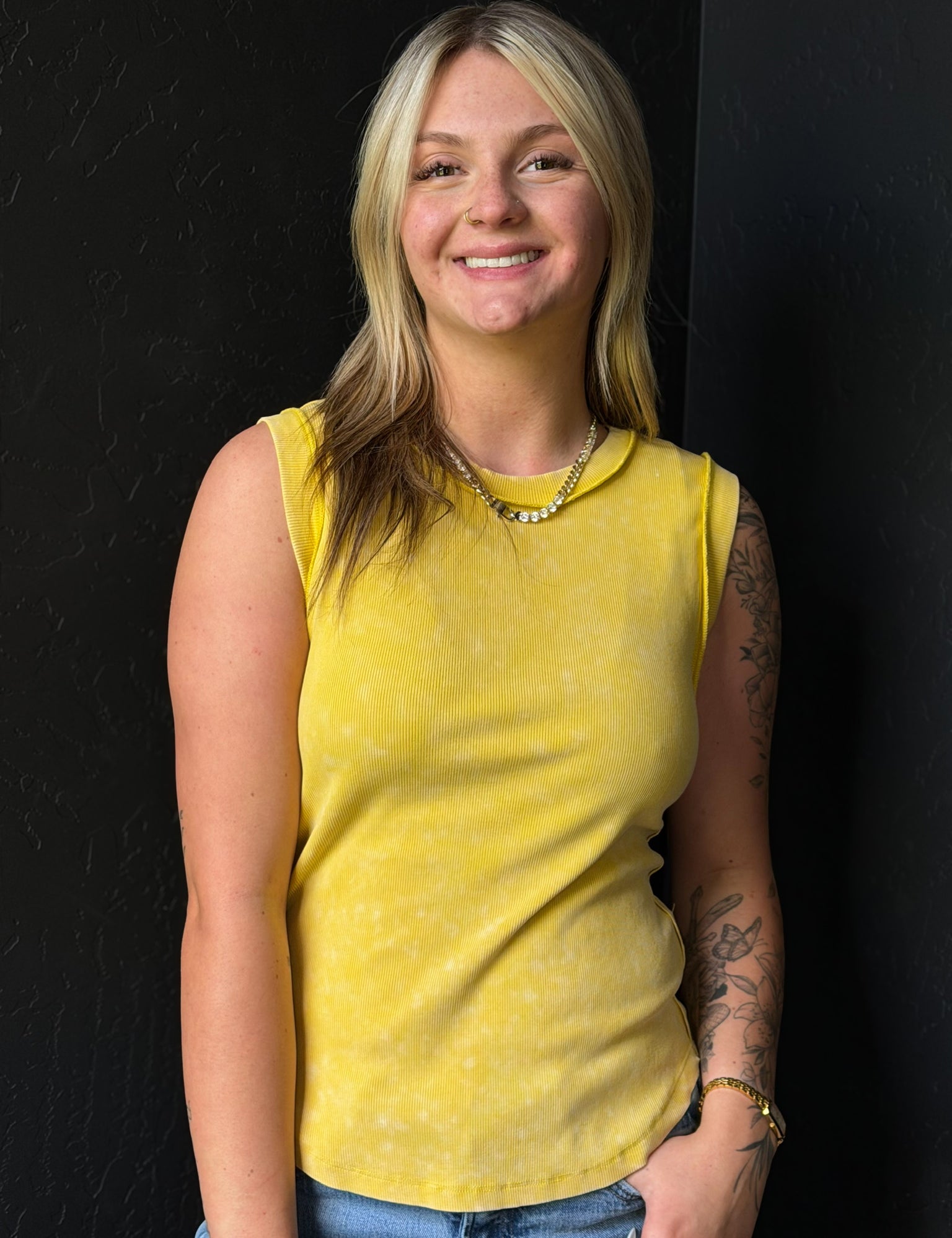 Woman wearing a yellow sleeveless top against a black background