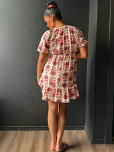 Woman wearing a floral dress against a dark gray wall.
