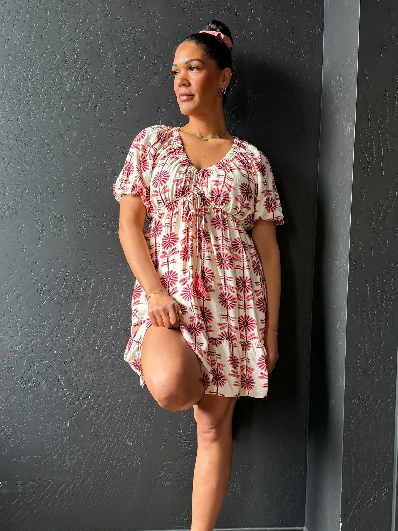 Woman wearing a floral dress against a dark gray wall