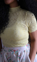 Person wearing a yellow lace top with a floral skirt