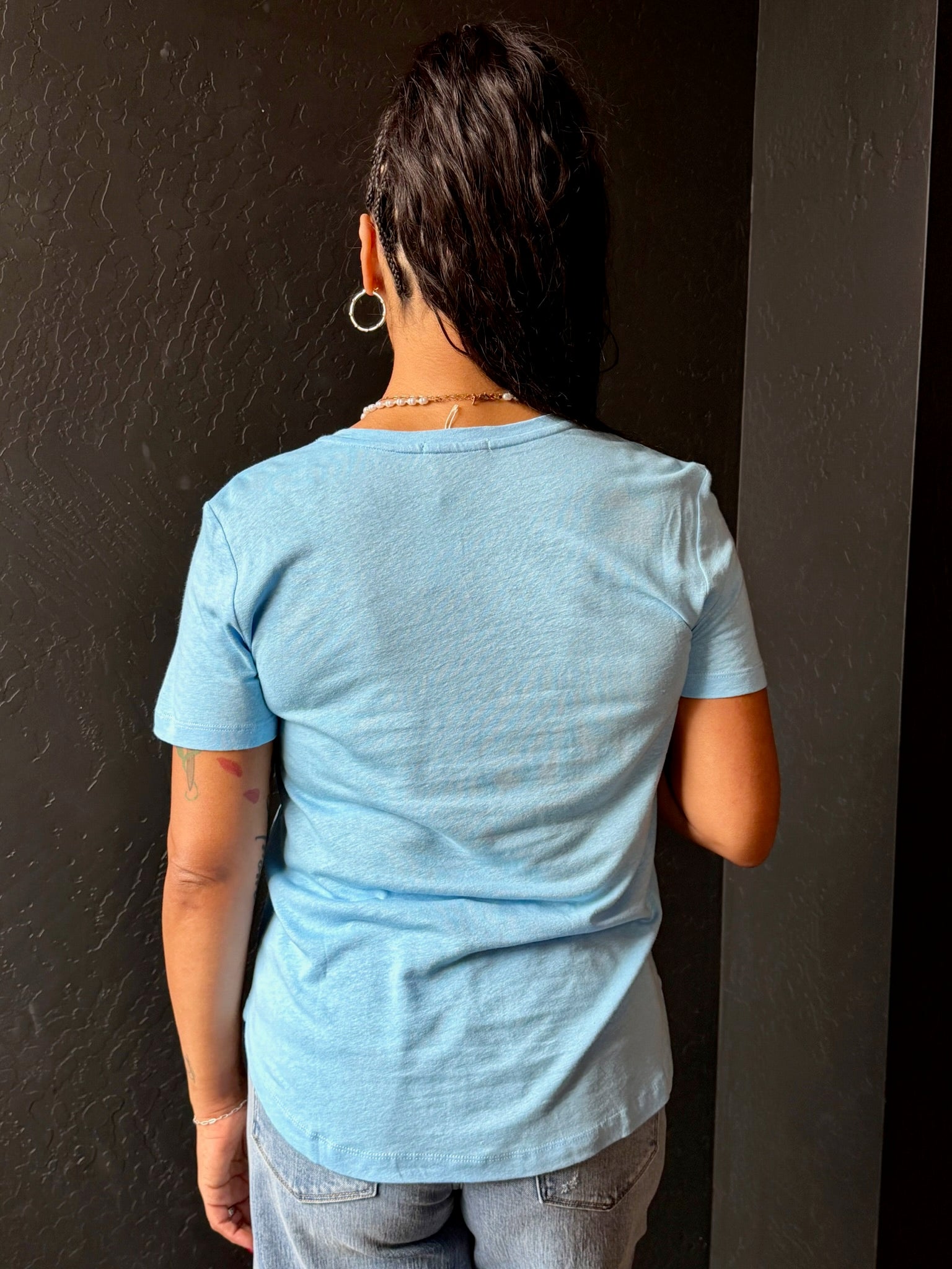 Person wearing a light blue t-shirt against a dark background