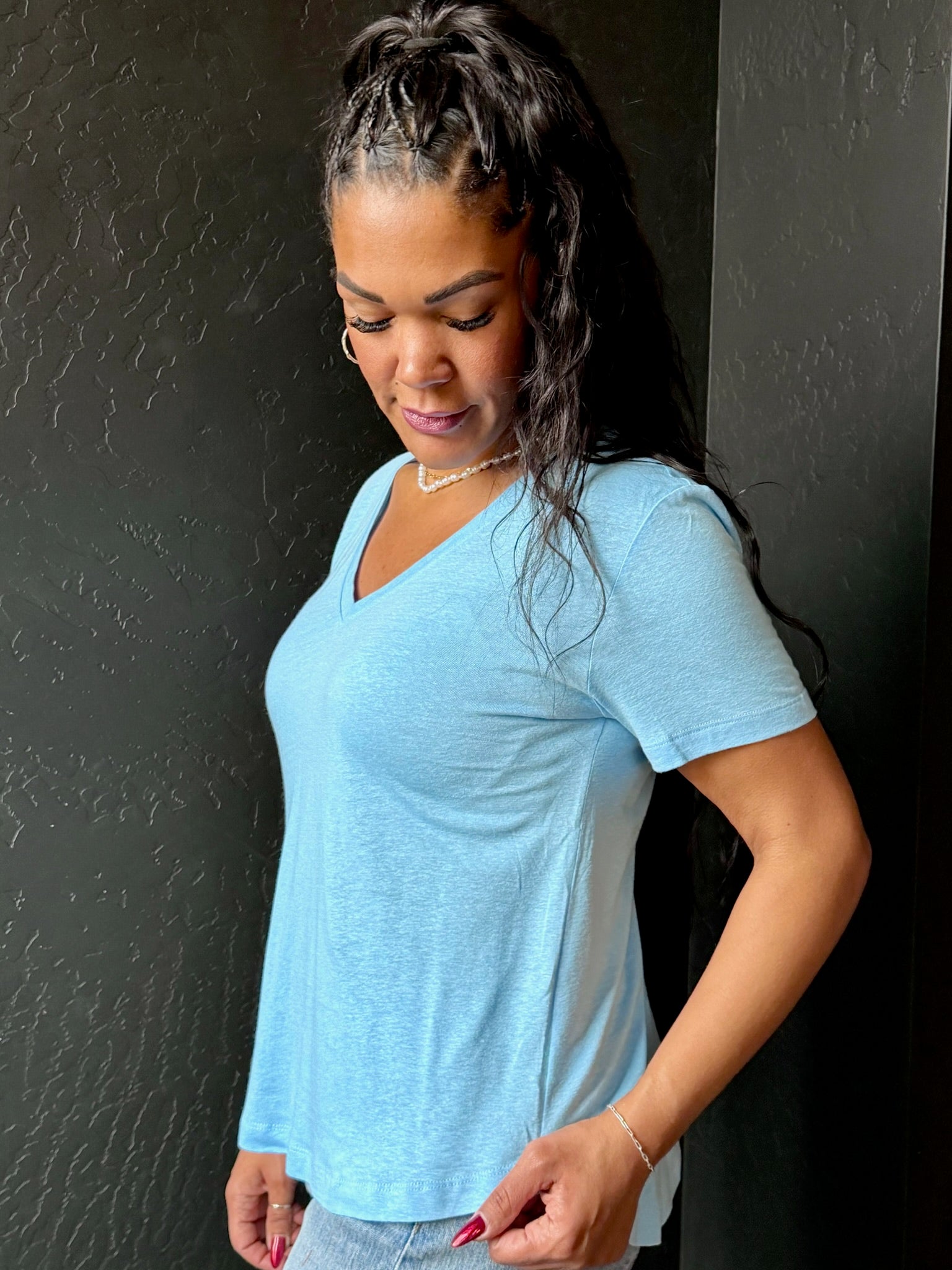 Woman wearing a light blue t-shirt against a black wall