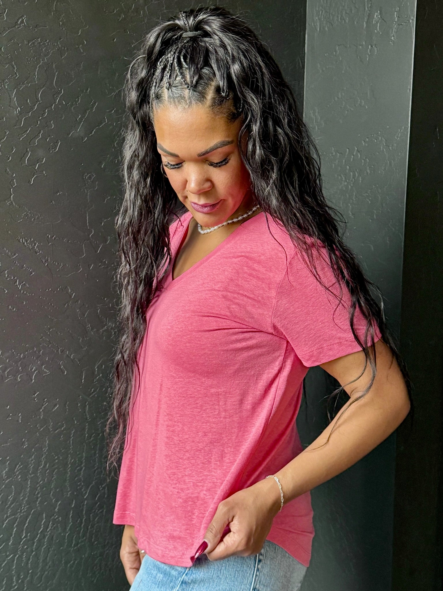 Woman wearing a pink shirt against a dark wall
