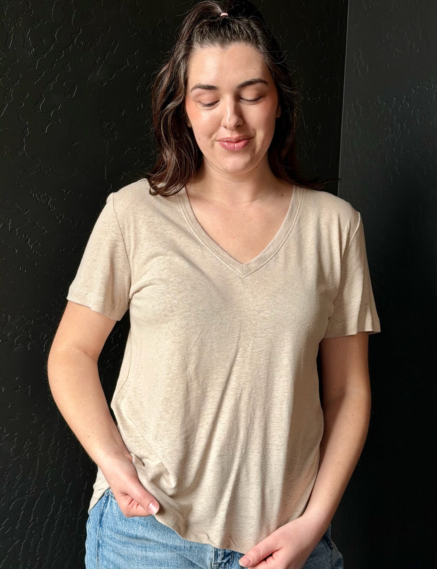 Woman wearing a beige t-shirt against a black background