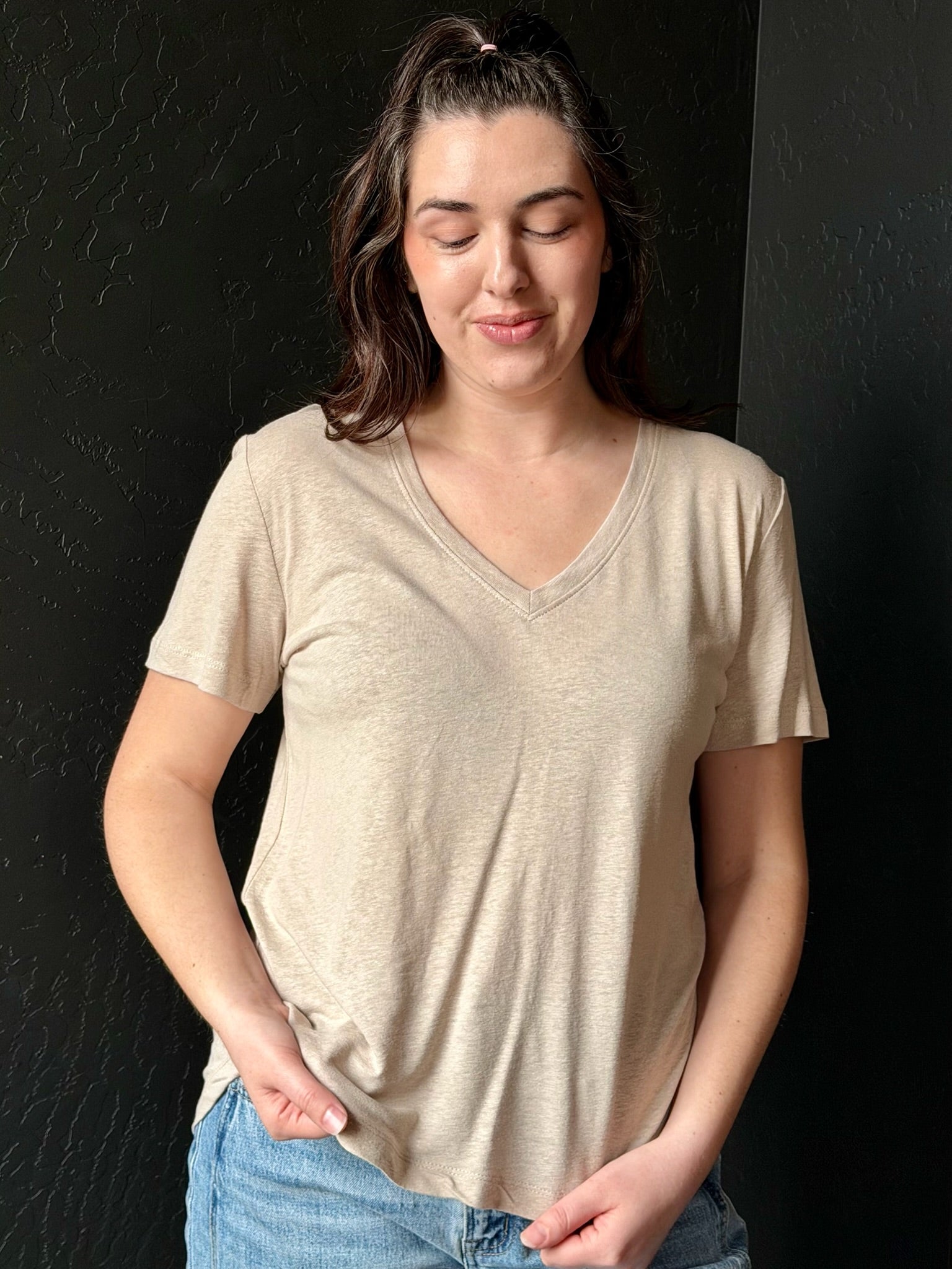 Woman wearing a beige t-shirt against a black background