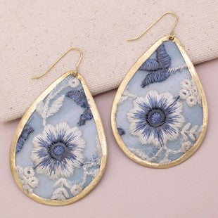 Teardrop-shaped earrings with floral design on a beige background