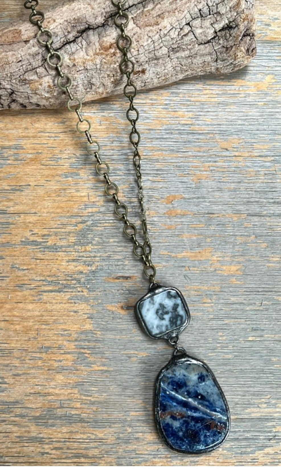 Necklace with two stone pendants on a wooden surface