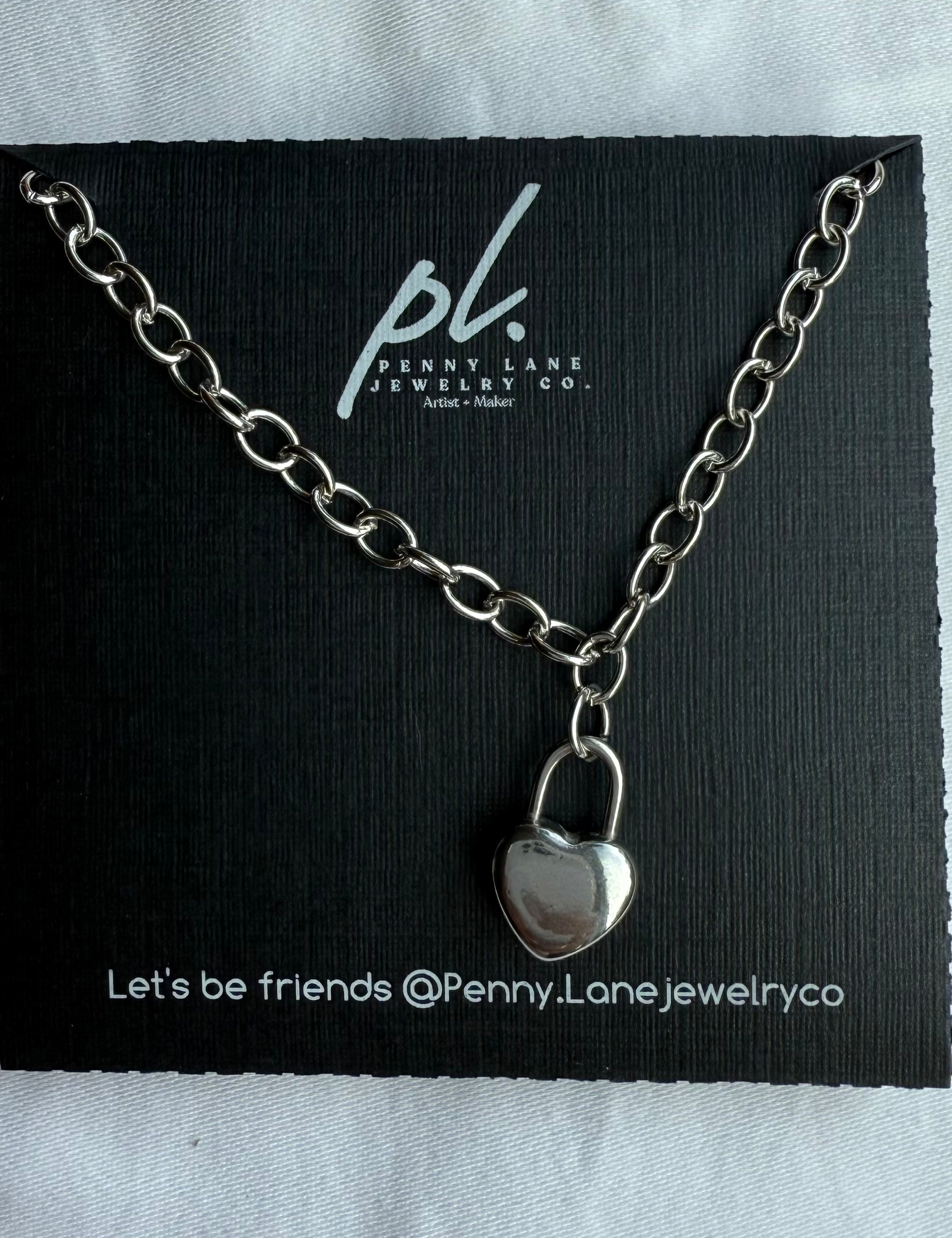Silver necklace with a lock pendant on a Penny Lane Jewelry Co card.