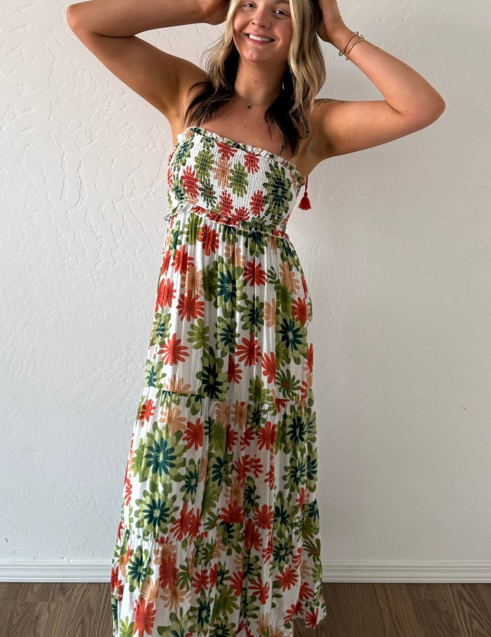 Woman wearing a floral strapless dress against a white wall.