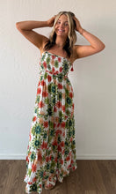 Woman wearing a floral strapless dress against a white wall.