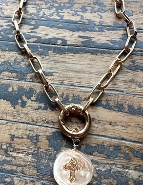 Necklace with a pendant featuring a cross on a wooden surface
