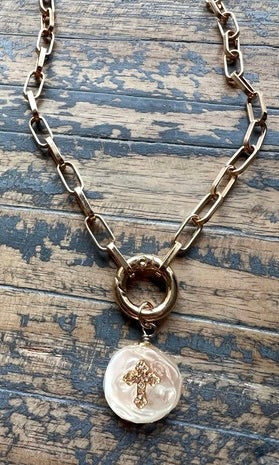 Necklace with a pendant featuring a cross on a wooden surface