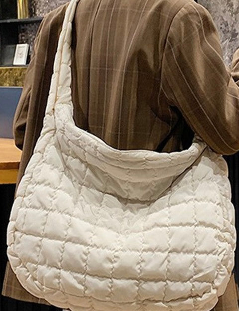 Person wearing a quilted white handbag with a neutral background
