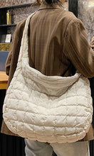 Person wearing a quilted white handbag with a neutral background