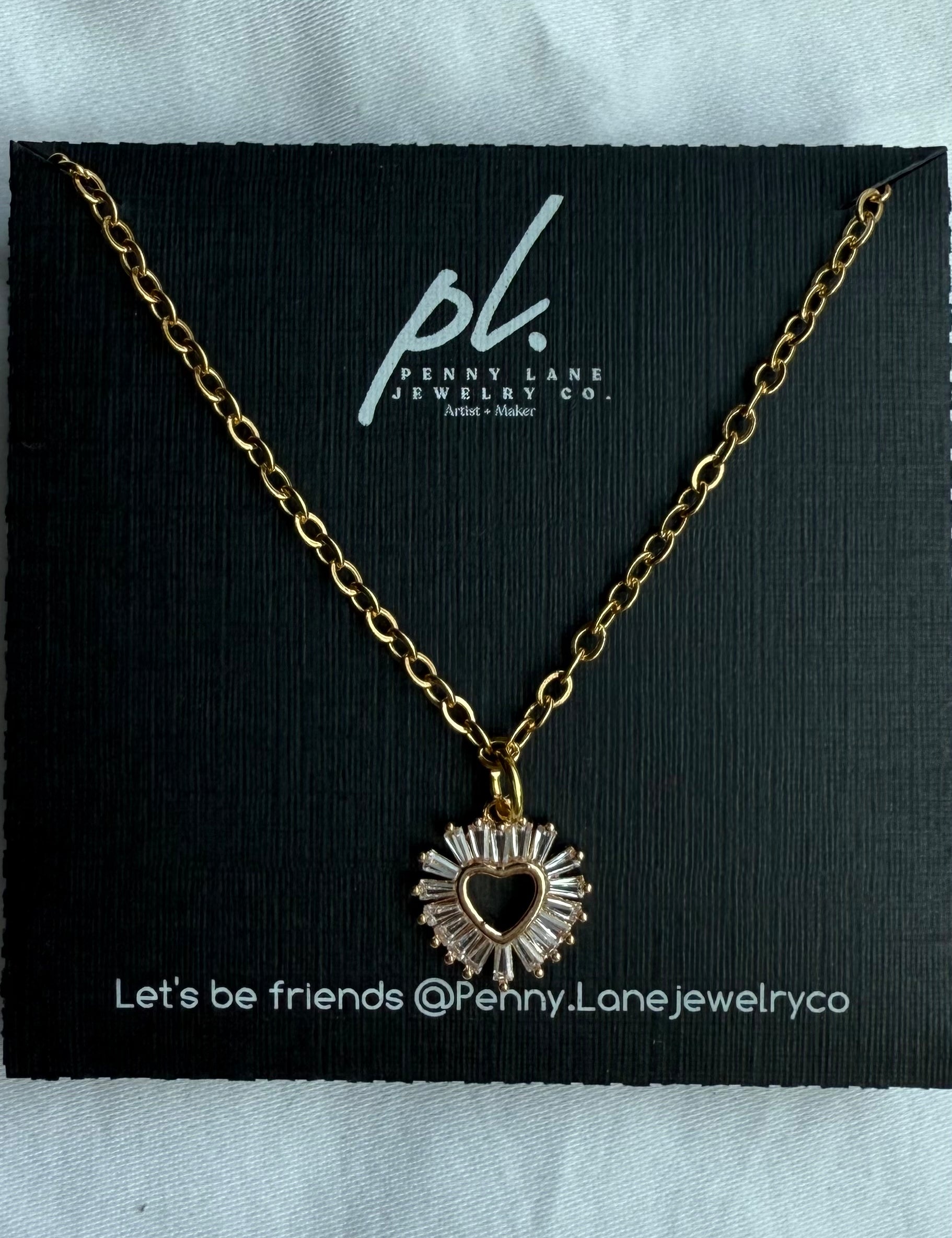 Gold necklace with a heart-shaped pendant on a Penny Lane Jewelry Co. card.
