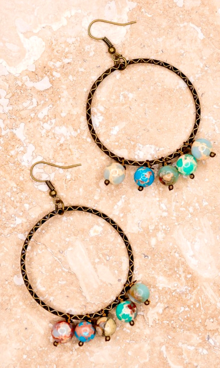 A pair of beaded hoop dangle earrings with a bronze metal fishhook closure, featuring multicolored beads.