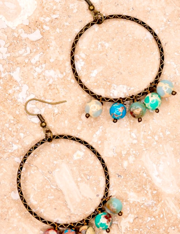A pair of beaded hoop dangle earrings with a bronze metal fishhook closure, featuring multicolored beads.