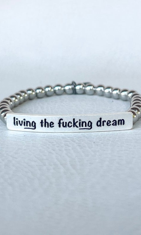 Silver bracelet with engraved text on a light gray background