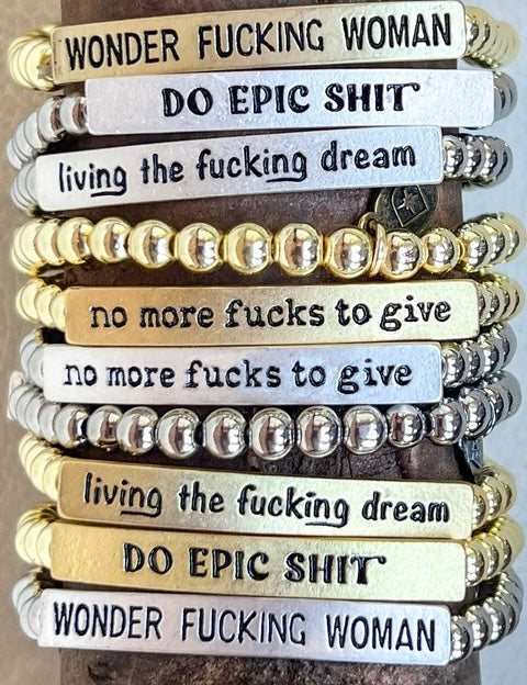 Stack of motivational bracelets with various phrases on a wooden background