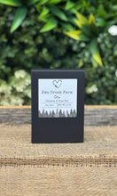 Small black box with a label on a wooden surface with greenery in the background