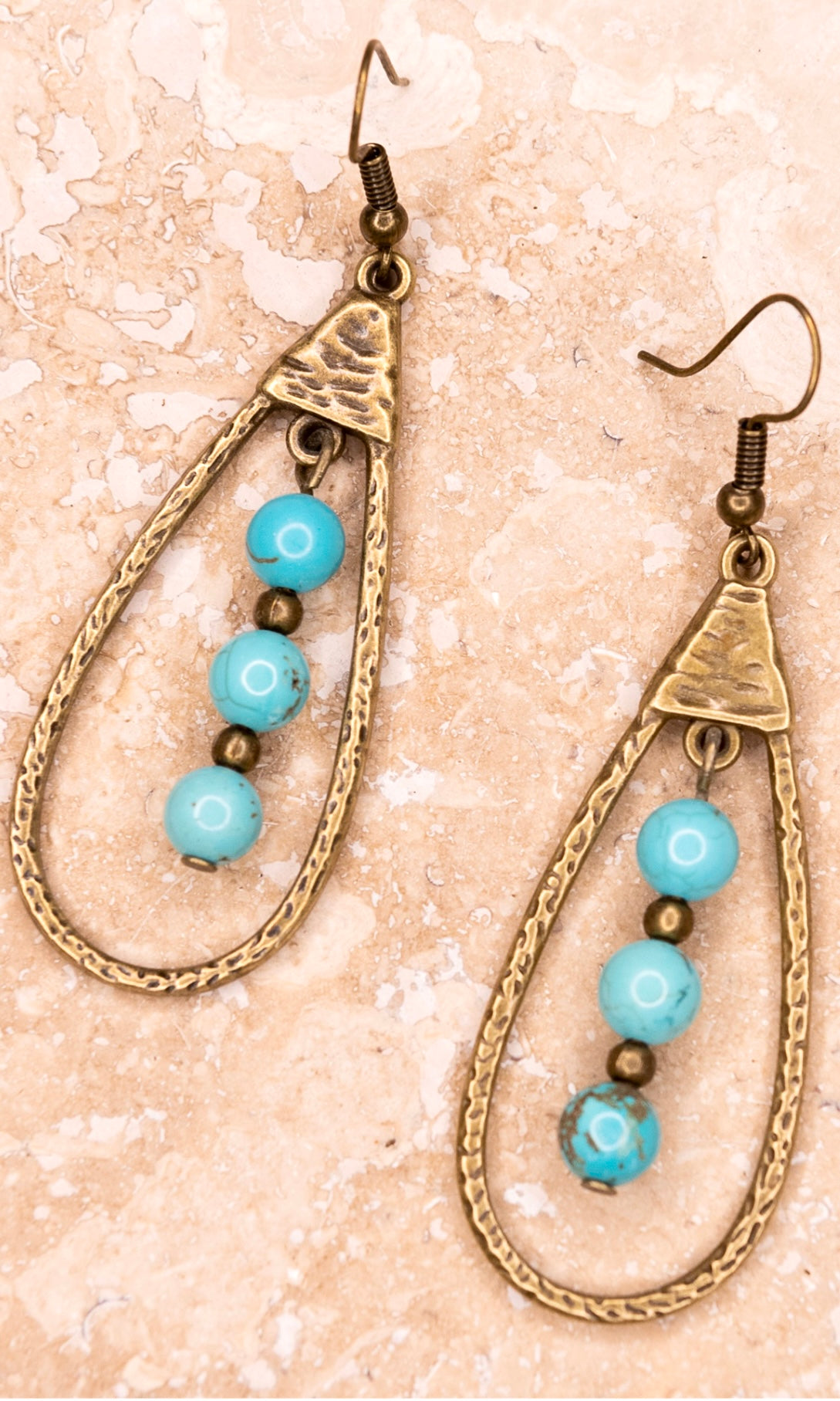 A pair of bronze teardrop-shaped dangle earrings with turquoise beads and brown accents.