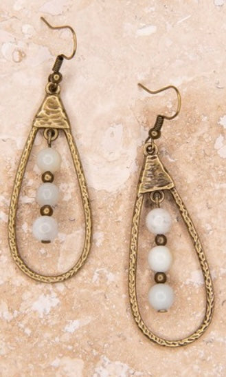 A pair of bronze teardrop-shaped dangle earrings with amazonite beads, displayed against a textured background.