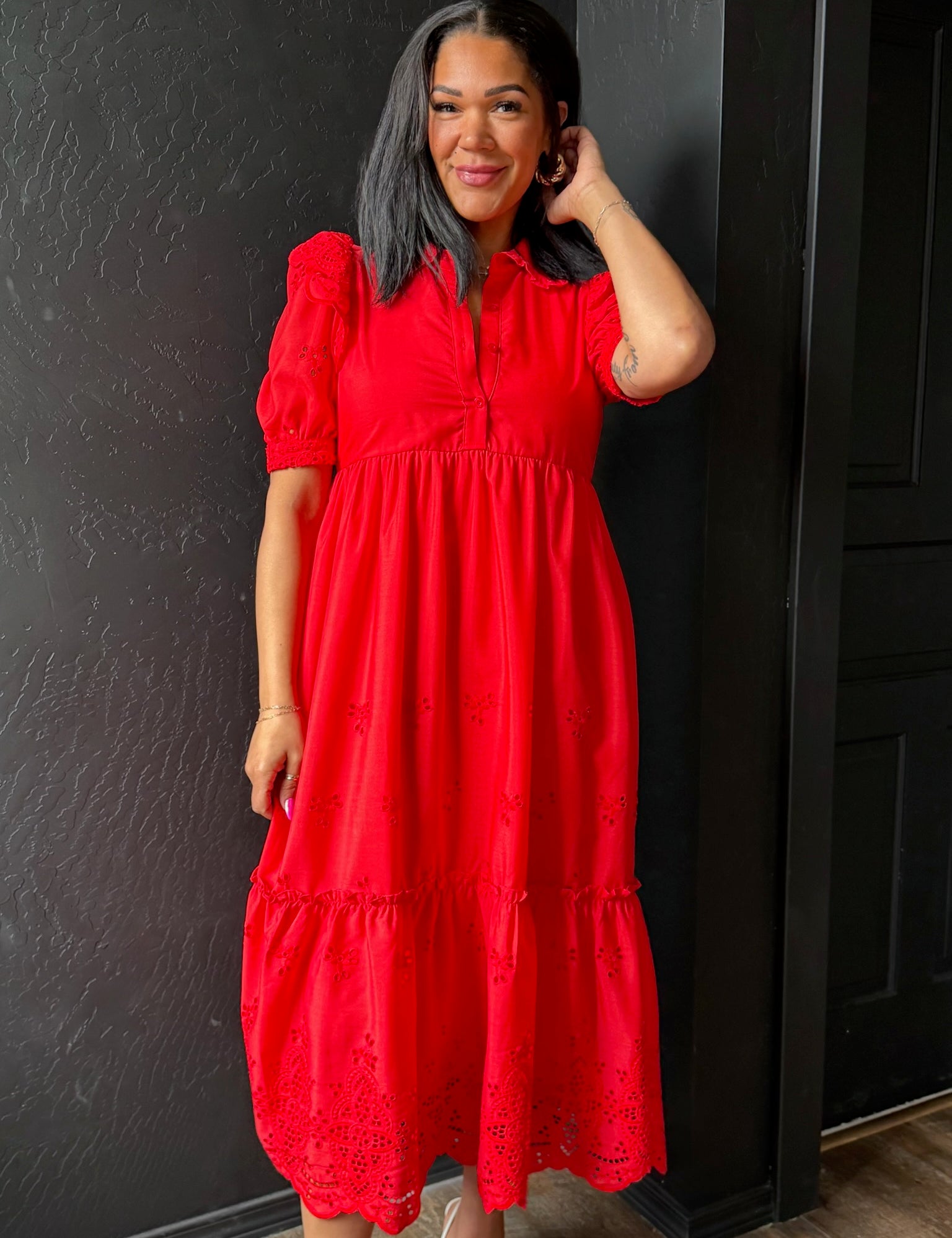 Woman wearing a red dress against a black wall