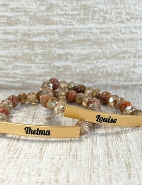 Two beaded bracelets with engraved names on a textured surface