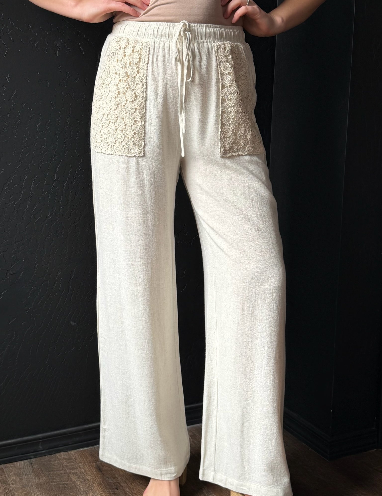 White pants with textured panels worn by a person against a dark background