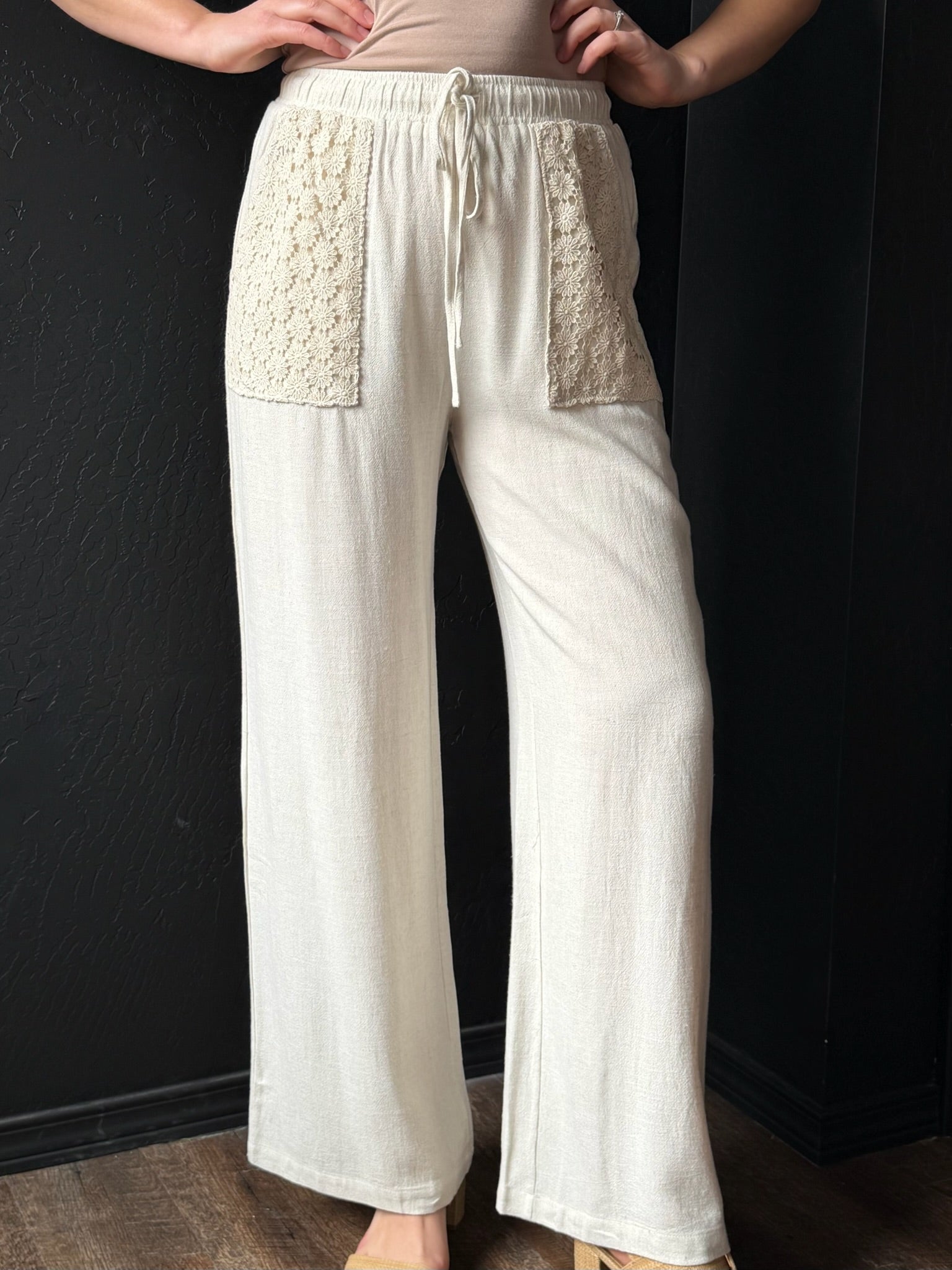 White pants with textured panels worn by a person against a dark background